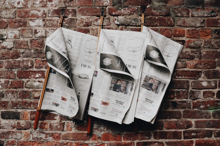 Three open newspapers on a wall